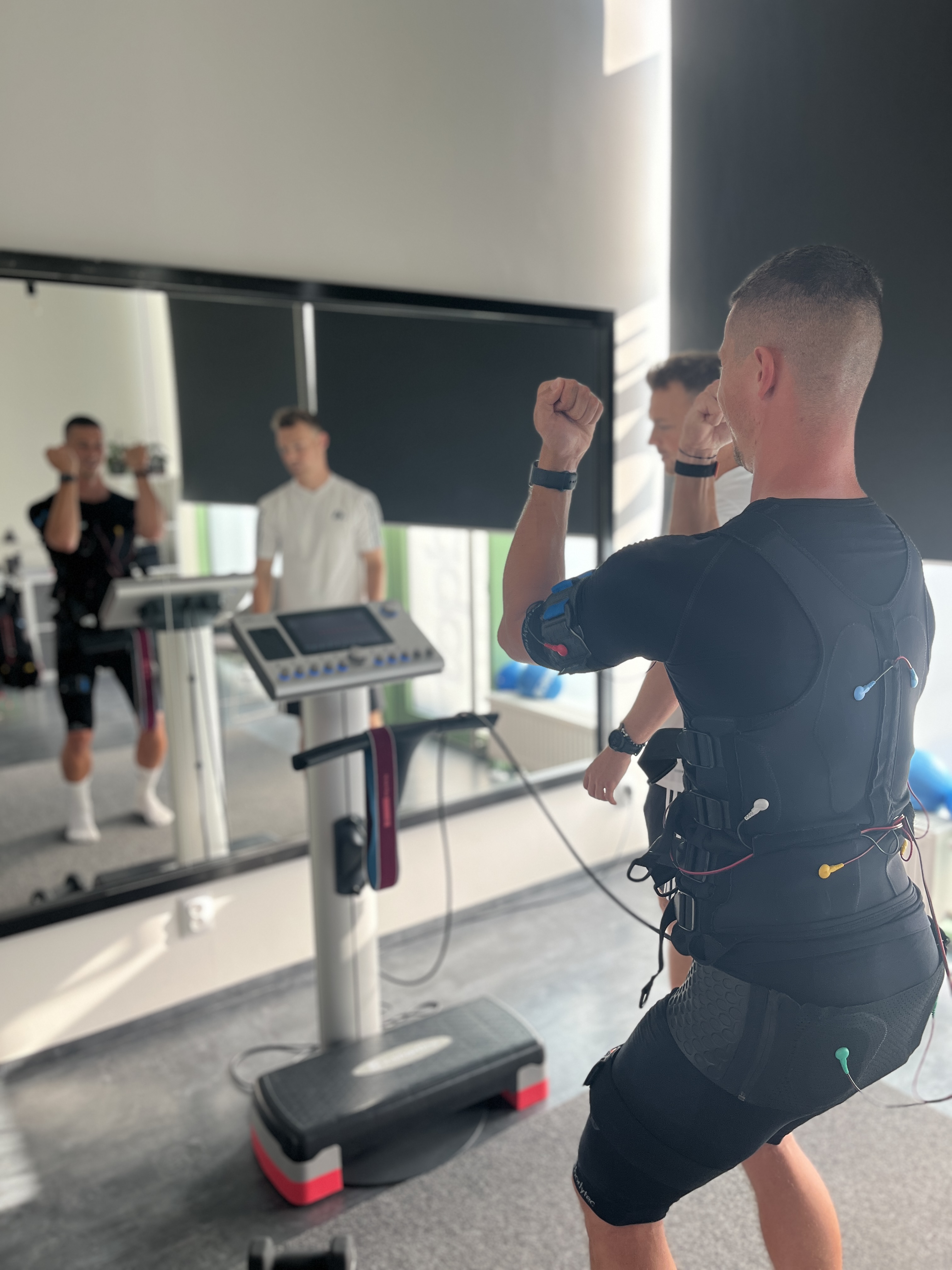 Muž cvičící s EMS přístrojem v podřepu